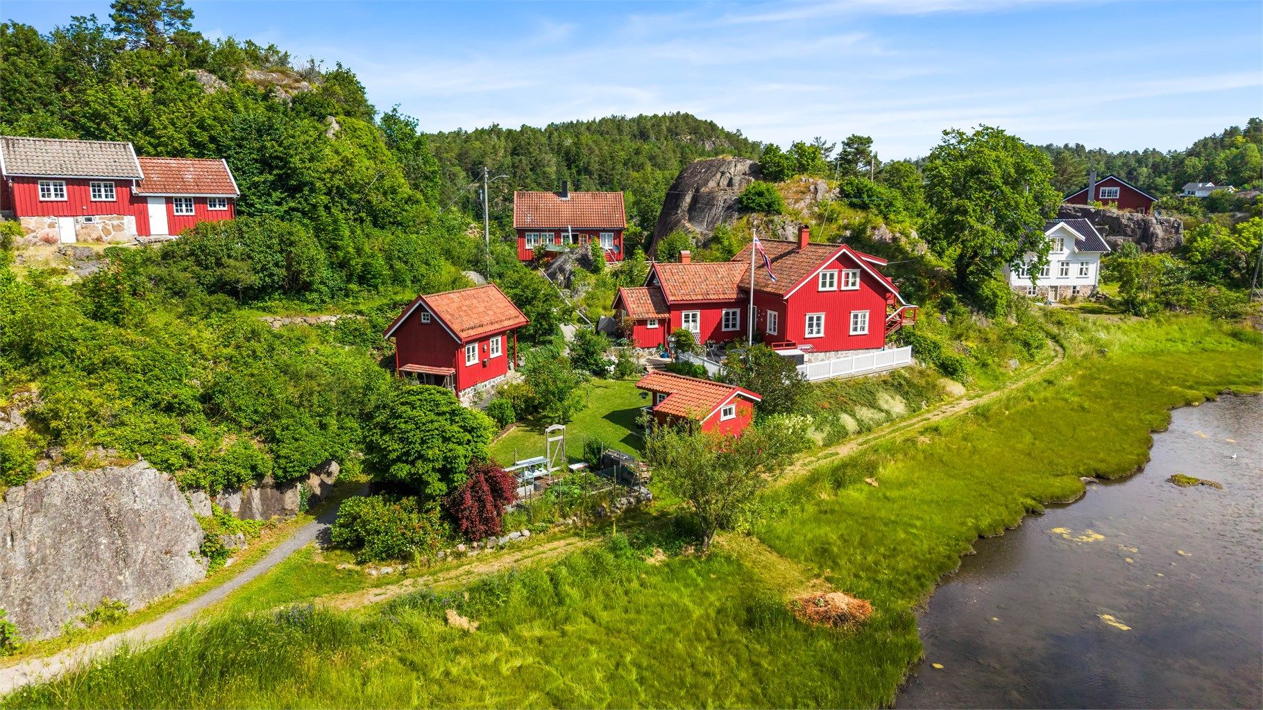 Oversikt over eiendommen med hovedhus og to uthus/boder.