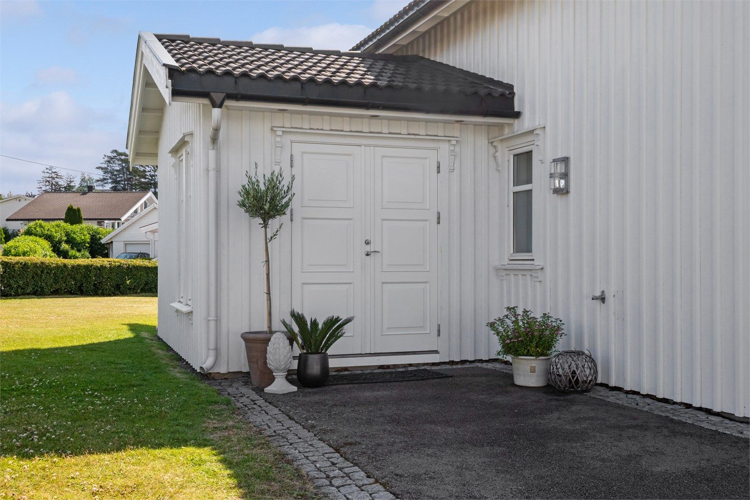 Ytterdøren er tofløyet og overbygd, og ved inngangen har boligen vannkran, downlights og plass til et koselig kafésett.