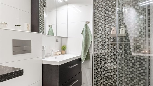 Badet har vegghengt toalett, servantmøbel med skuffer og speilskap med integrert belysning.