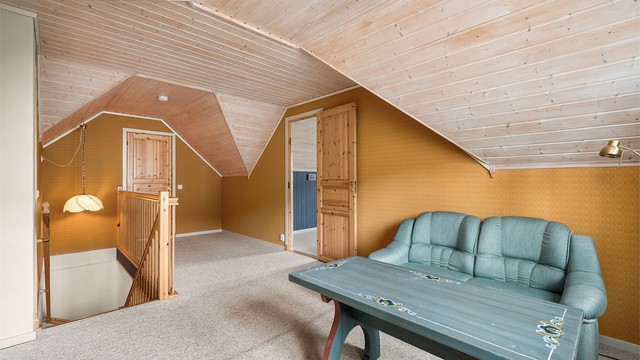 Loftstuen fremstår som et lunt og hyggelig oppholdsrom med skråhimling som gir særpreg og en ekstra koselig atmosfære.