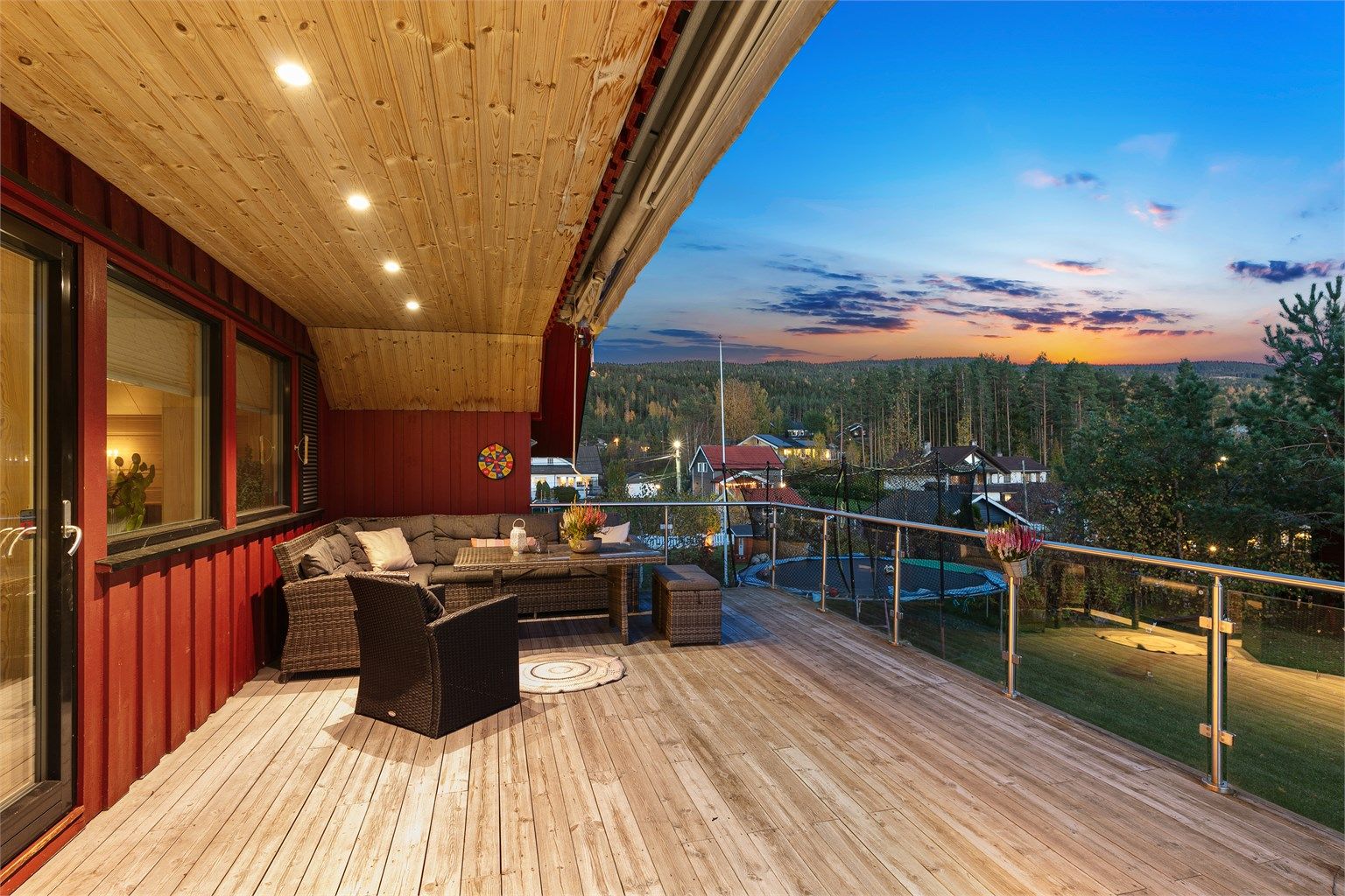 Sørøstvendt terrasse over to nivåer med glassrekkverk.