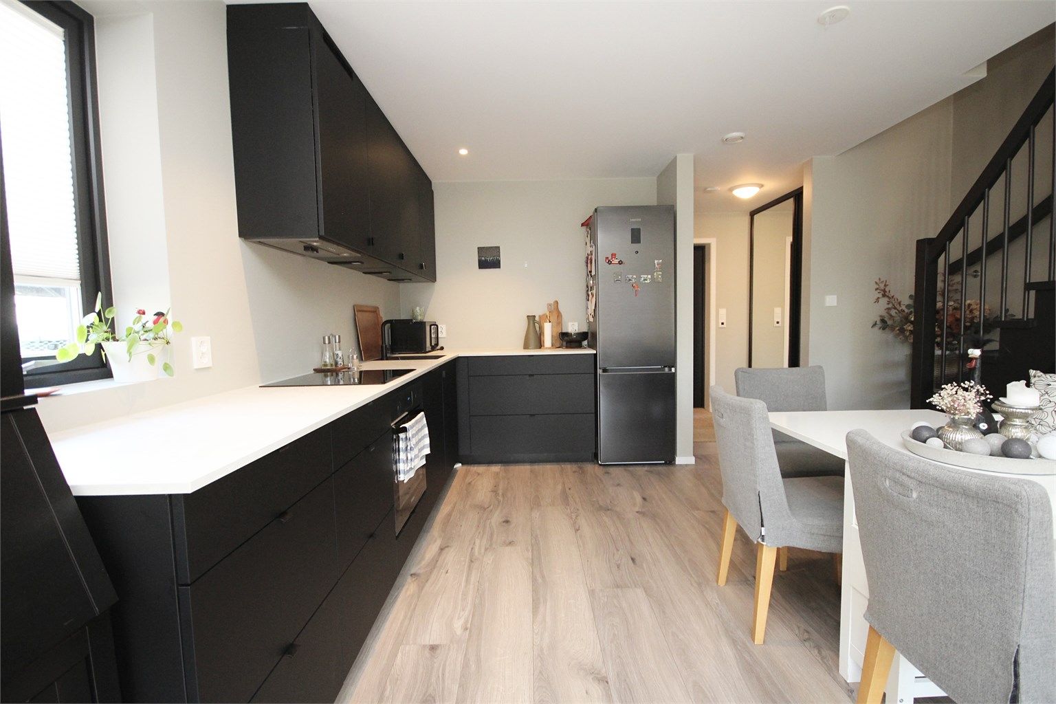 Kjøkken med åpen løsning mot stue. Lekre svarte fronter og integrerte hvitevarer. 