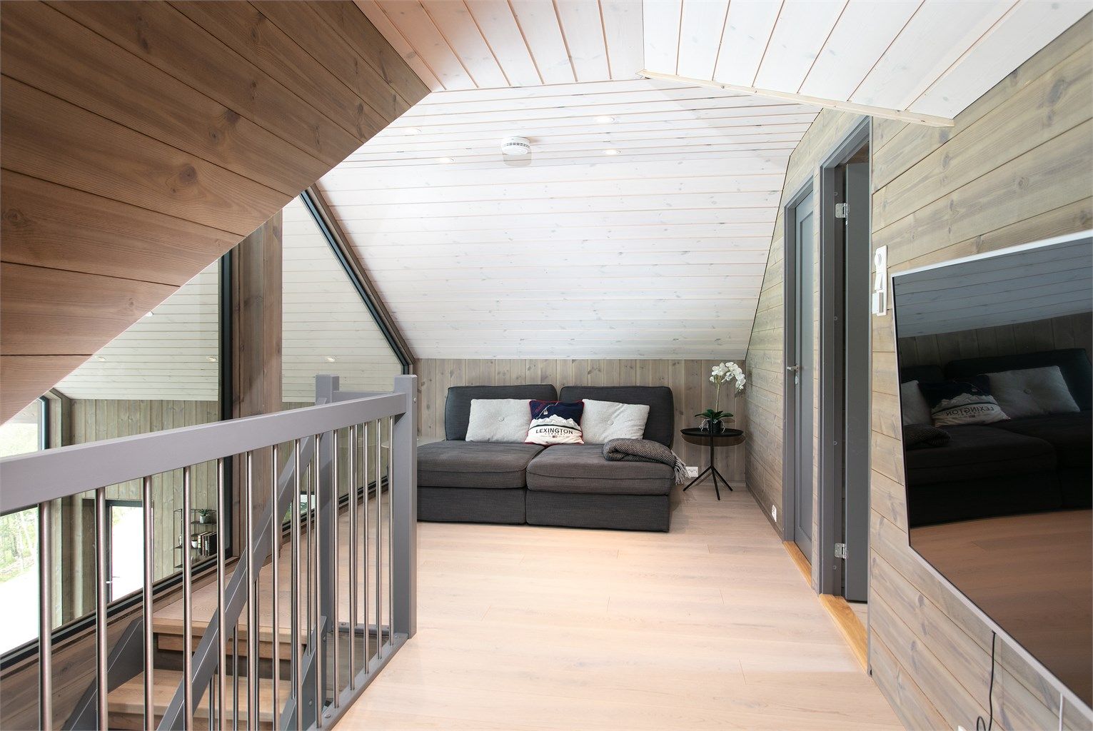 Koselig loftstue med skråhimling, innfelte spotter og god plass til sittegruppe og TV.