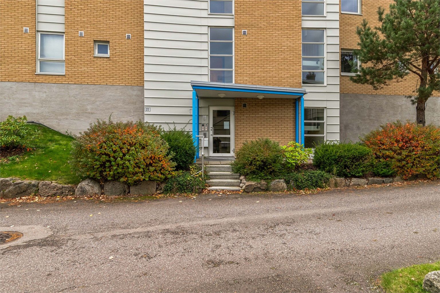 Overbygd inngangsparti med callinganlegg med kamera og heis i bygget.