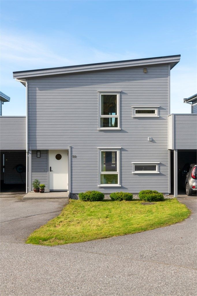 Inngangsparti og carport på fremsiden av boligen med asfaltert adkomst.