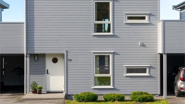 Inngangsparti og carport på fremsiden av boligen med asfaltert adkomst.