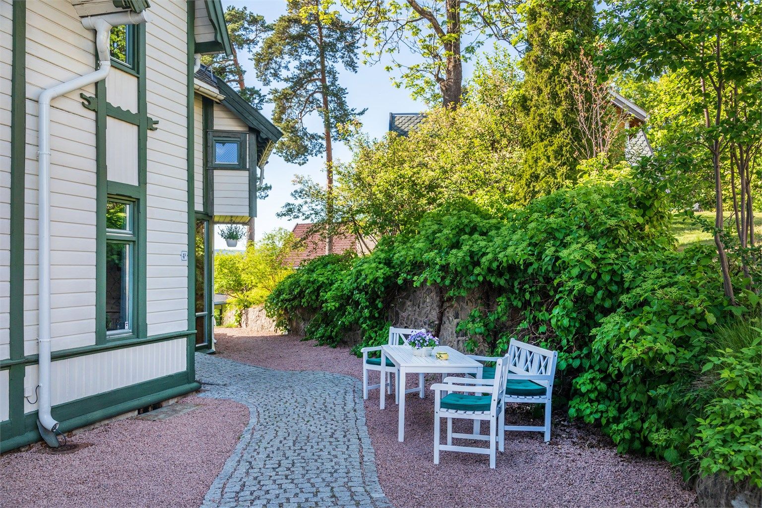 Gangsti belagt med belegningsstein og grus rundt deler av huset