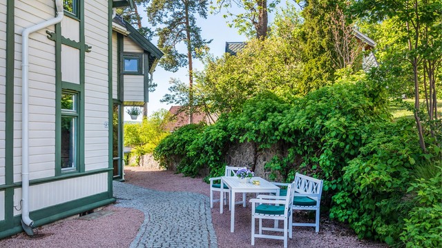 Gangsti belagt med belegningsstein og grus rundt deler av huset