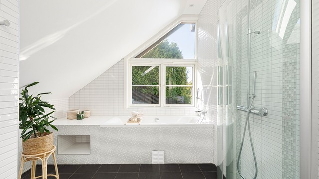 Badet byr på gulvvarme, innfellbare dusjdører, regndusj og hånddusj, innebygget flislagt badekar, vegghengt toalett og mekanisk avtrekk