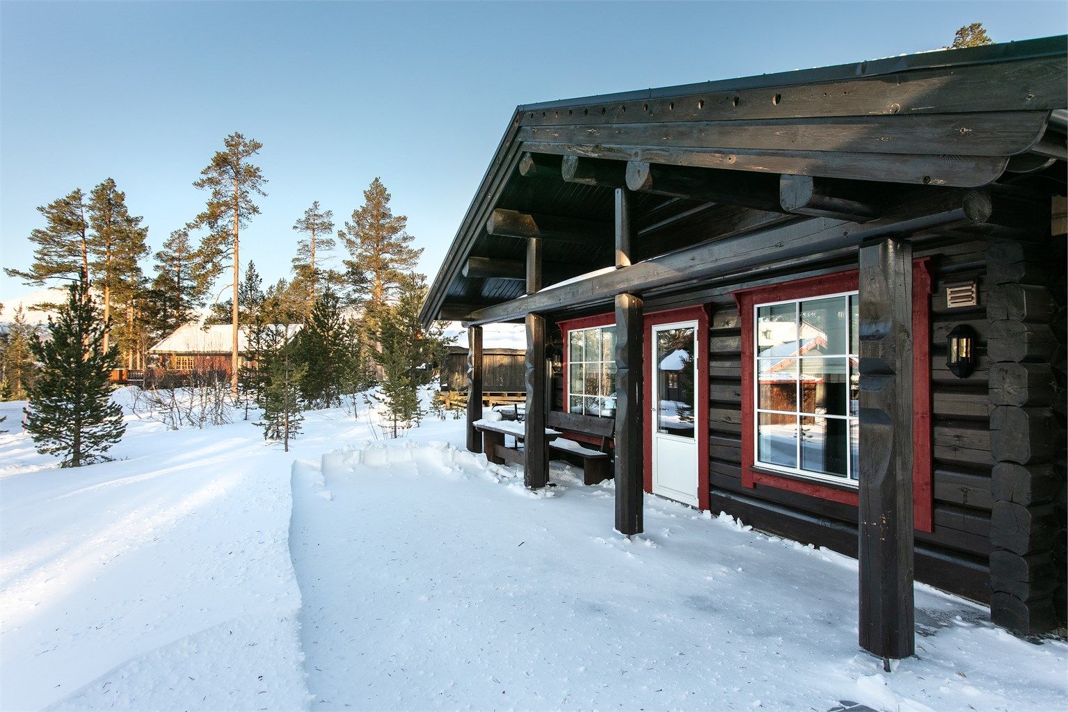 Stor støpt terrasse rundt deler av hytten med flere soner og sitteplasser