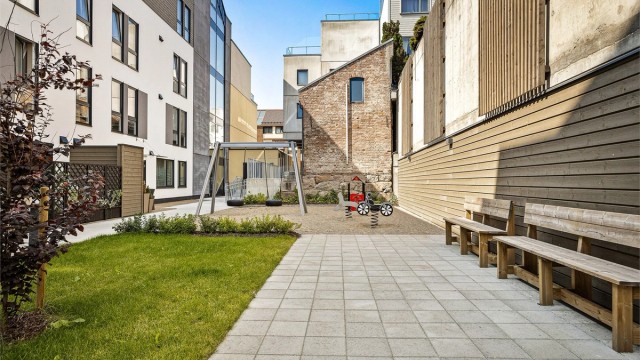 Leiligheten har tilgang til hyggelig bakgård med felles sykkelparkering samt lekeplass med lekeapparater - Sommerbilde fra tidligere annonse.