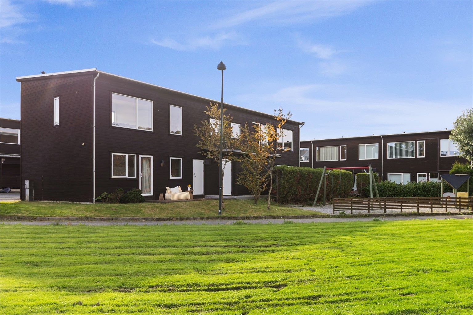 Store, velholdte fellesarealer med gressplen og lekeapparater like utenfor boligen.