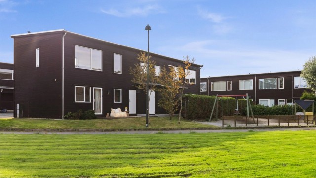 Store, velholdte fellesarealer med gressplen og lekeapparater like utenfor boligen.
