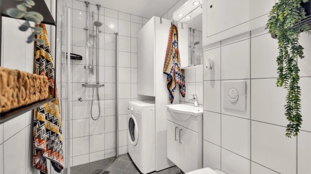 Pent flislagt baderom fra 2015 med grå og hvite fliser på henholdsvis gulv og vegger.