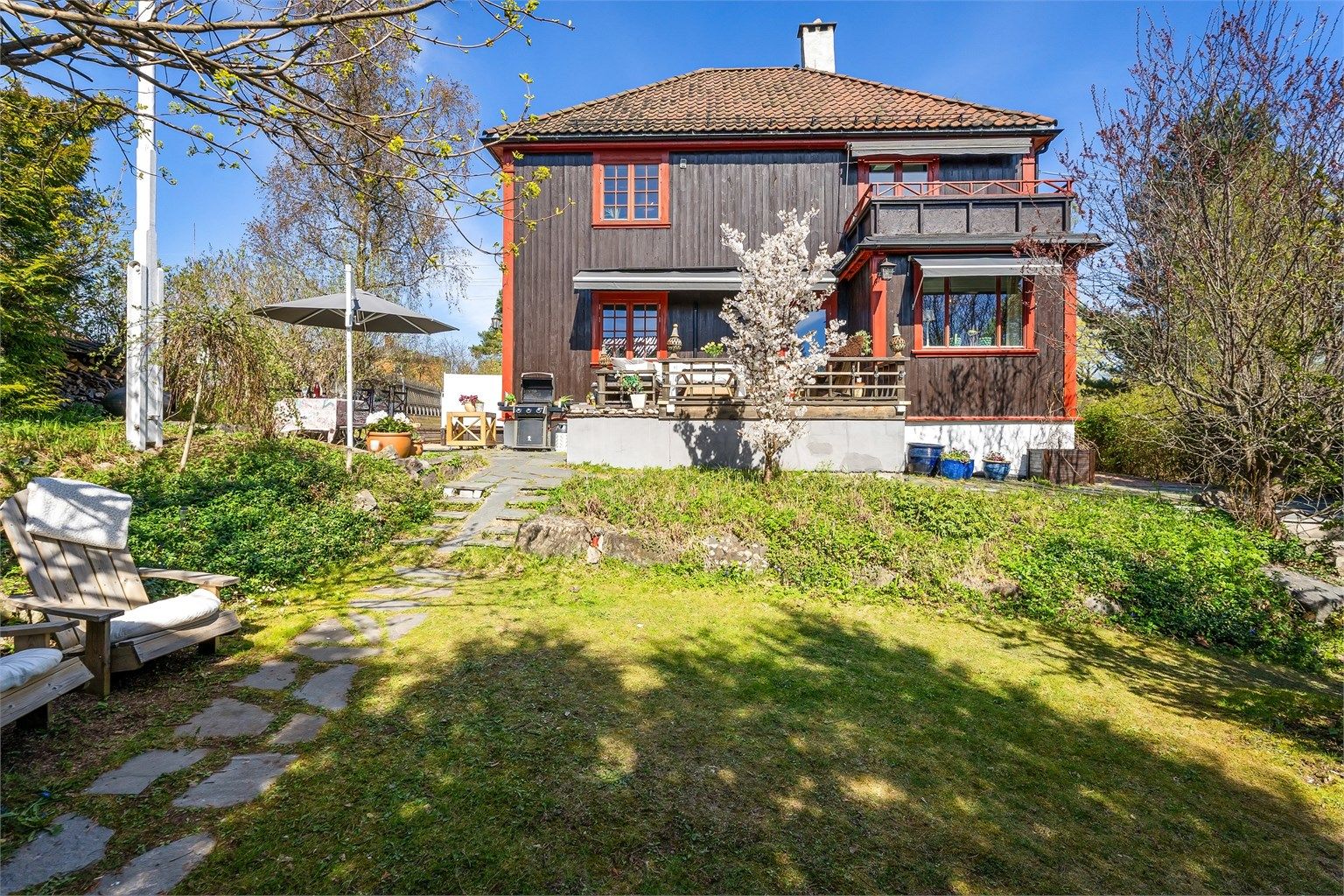 Eneboligen har en klassisk arkitektur med stående trekledning og valmtak.