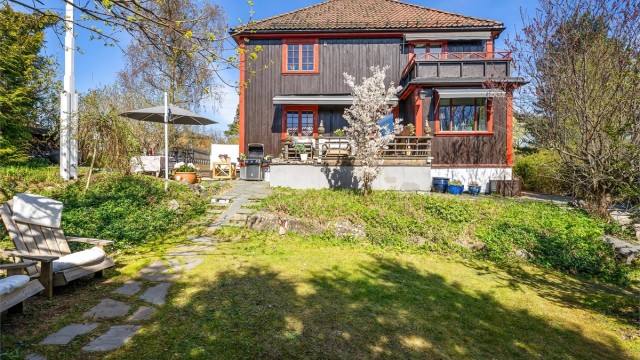 Eneboligen har en klassisk arkitektur med stående trekledning og valmtak.