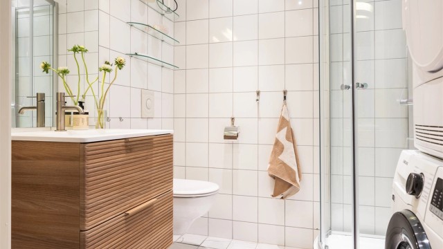 Lyst, flislagt baderom med hovedkonstruksjoner fra byggeårene. Lekkert servantskap nytt i 2026.