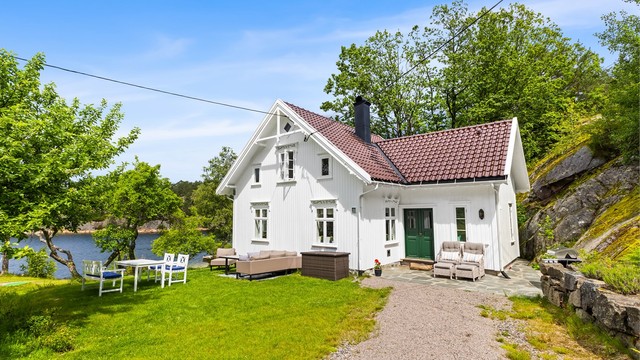 Det hvite hovedhuset er nylig renovert og tilbygget, og fremstår friskt og innbydende. Utenfor er det koselig hage med gamle frukttrær og nydelig utsikt mot vannet.