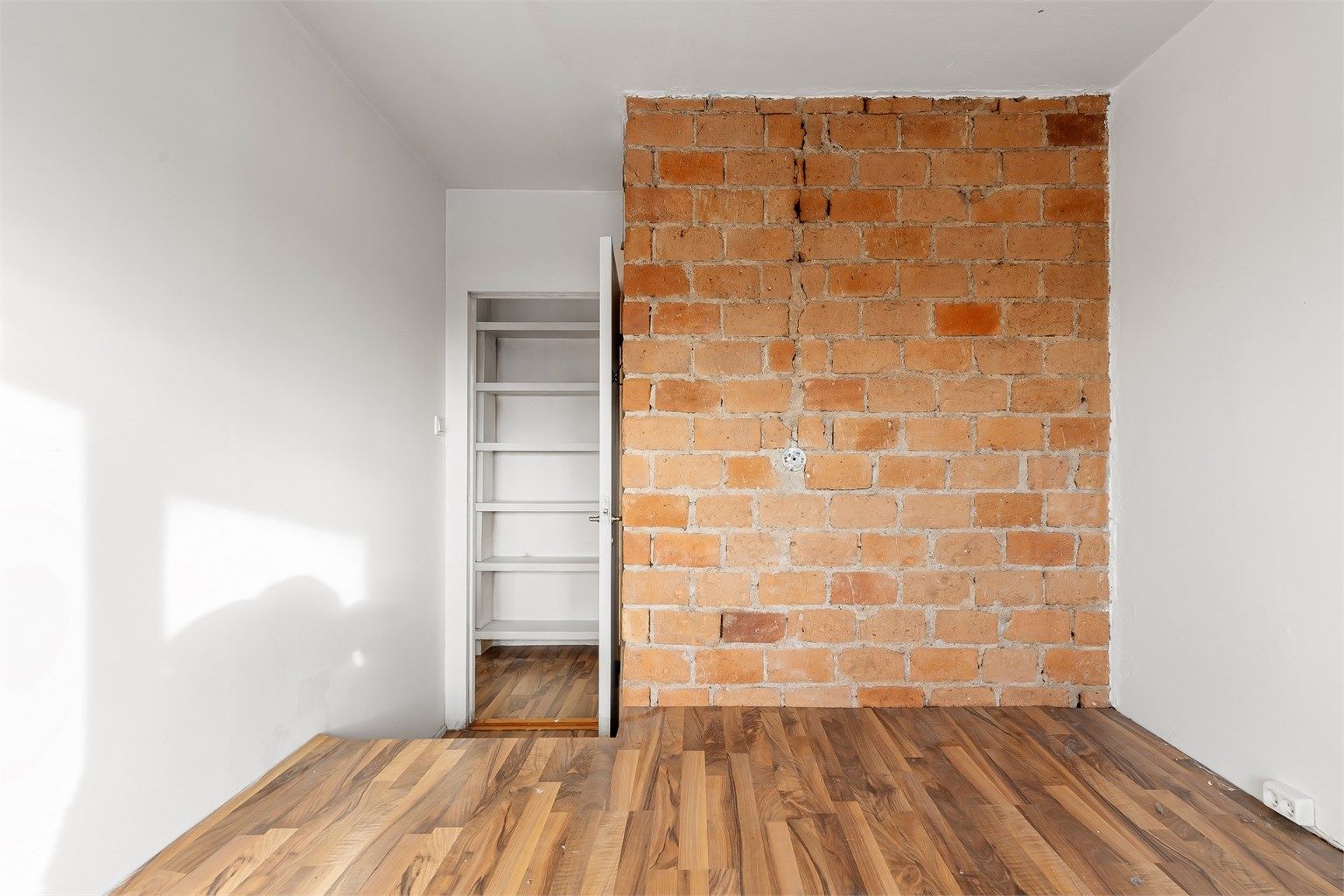 En eksponert teglsteinsvegg gir karakter til rommet, som også har en tilknyttet bod.