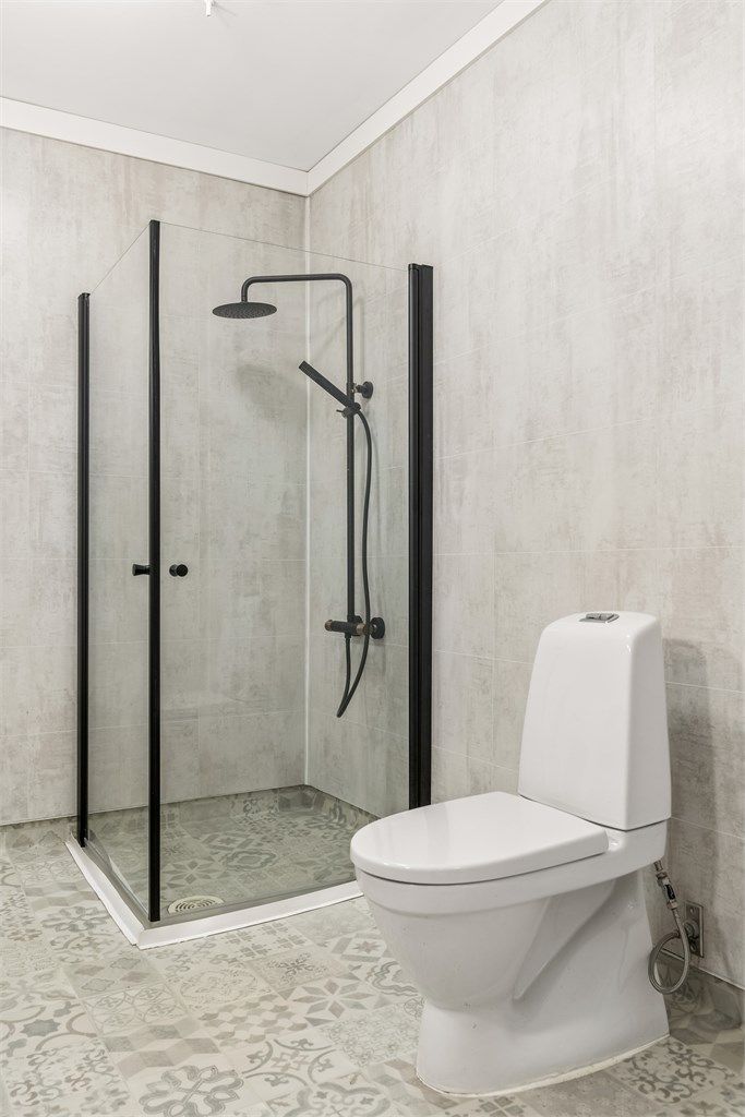 Badet har stilig gulvbelegg med gulvvarme, baderomsplater på veggene og innredning med servant, speil og dusjhjørne.