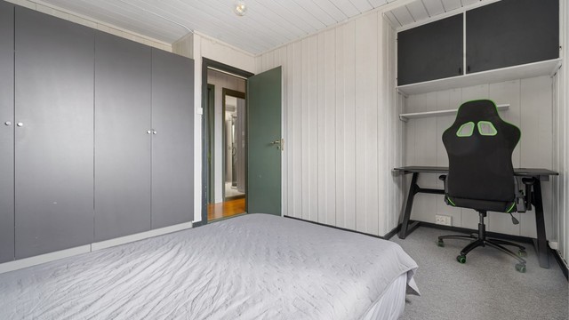Et av boligens tre soverom, med plass til både seng, garderobe og en egen arbeidspult.