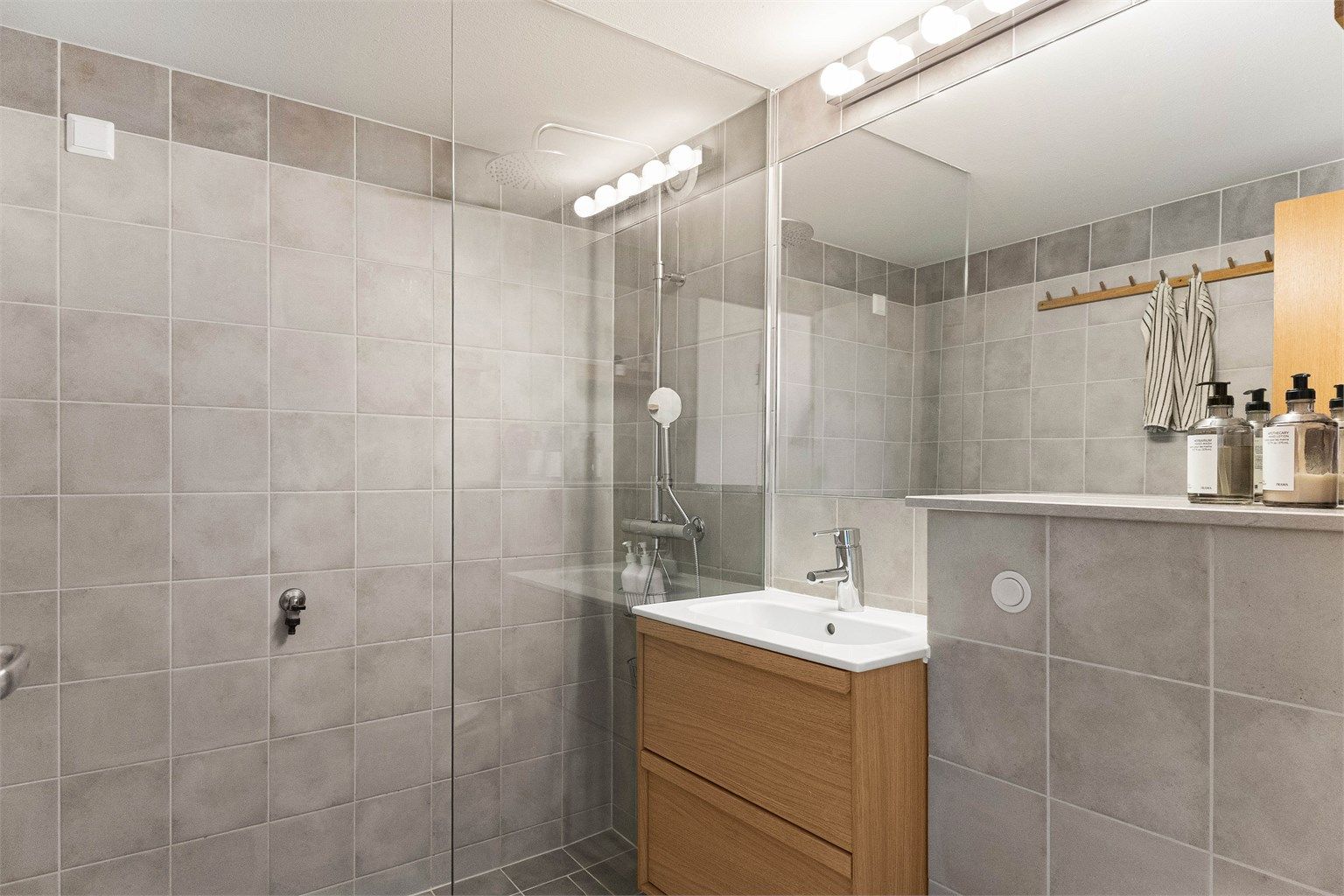Badet i 7. etasje er helflislagt med elektrisk gulvvarme, vegghengt toalett og dusjhjørne i glass og har et et rent og gjennomført uttrykk.