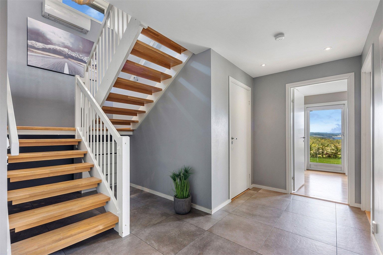 Fra hallen fører en solid svingtrapp i tre deg opp til boligens sosiale sone i andre etasje.