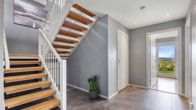 Fra hallen fører en solid svingtrapp i tre deg opp til boligens sosiale sone i andre etasje.