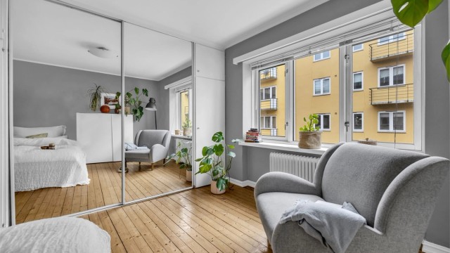 Store vindusflater i kombinasjon med takhøyden gir rommet en lys og luftig atmosfære.