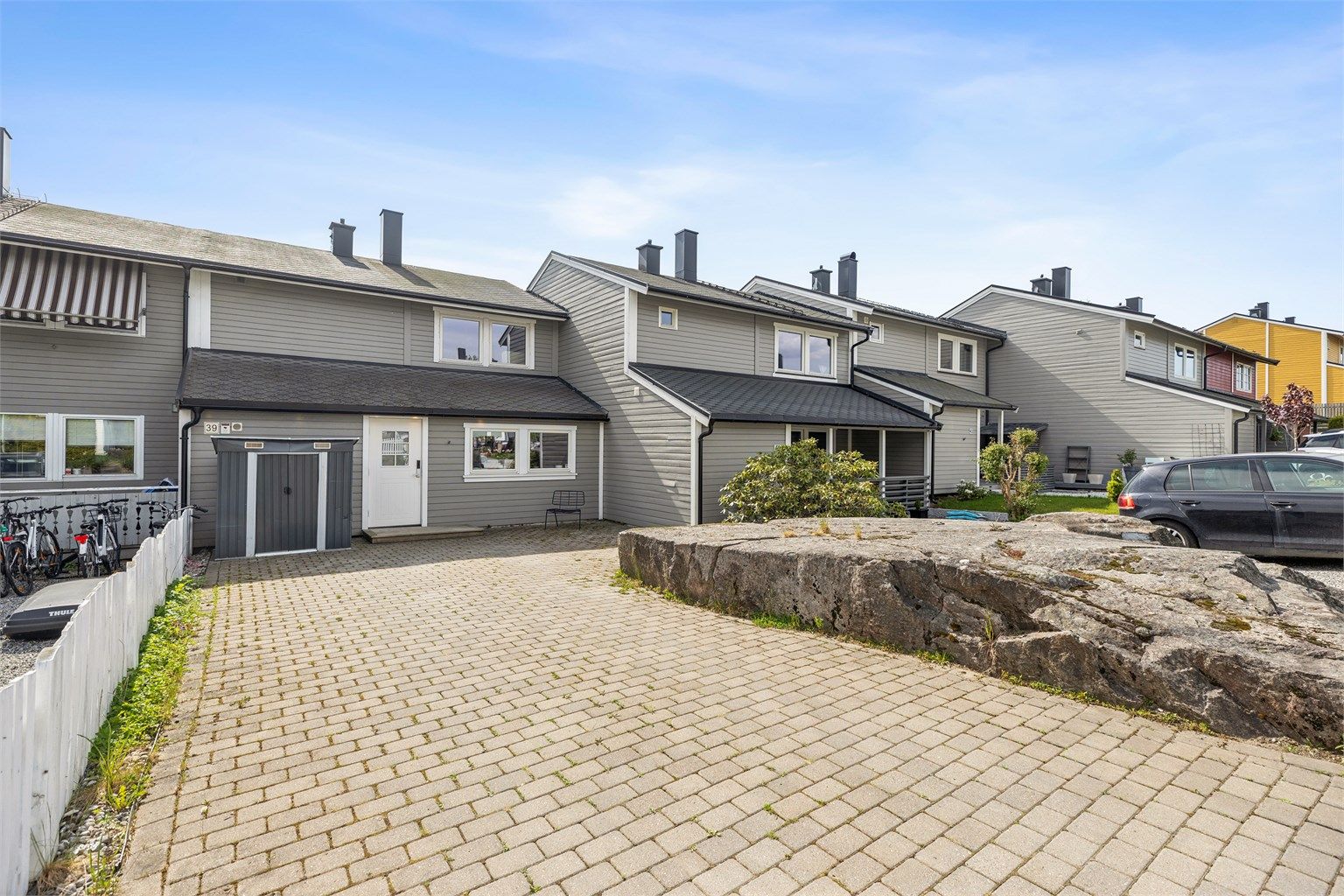 Man ankommer boligen via oppkjørsel og hyggelig terrasse med belegningsstein på forsiden av boligen