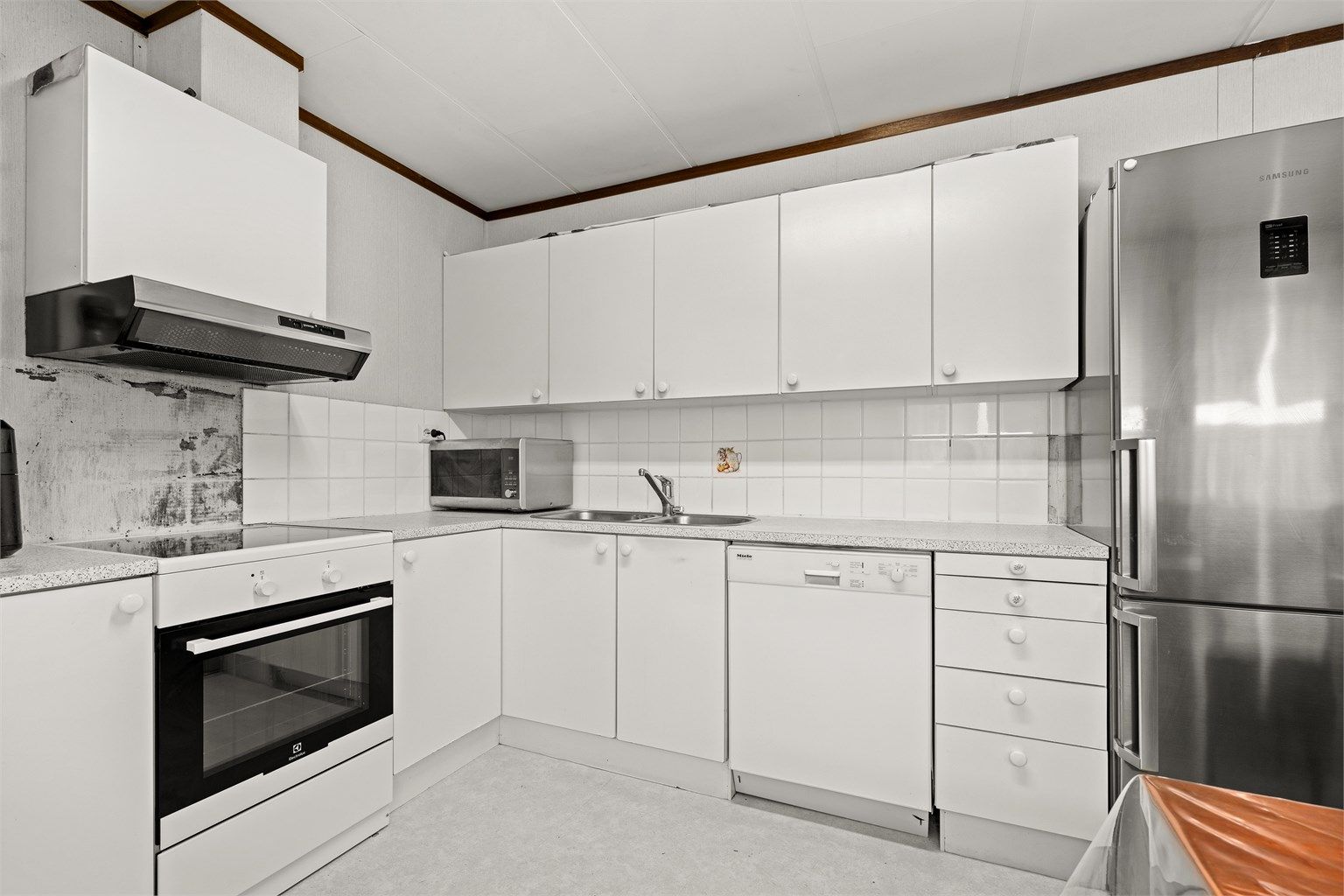 Kjøkken fra byggeår med innredning med glatte fronter og laminert benkeplate.