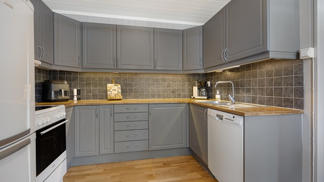 Kjøkkeninnredning fra Sigdal med malte, glatte fronter og laminat benkeplate. Det er opplegg for frittstående hvitevarer.