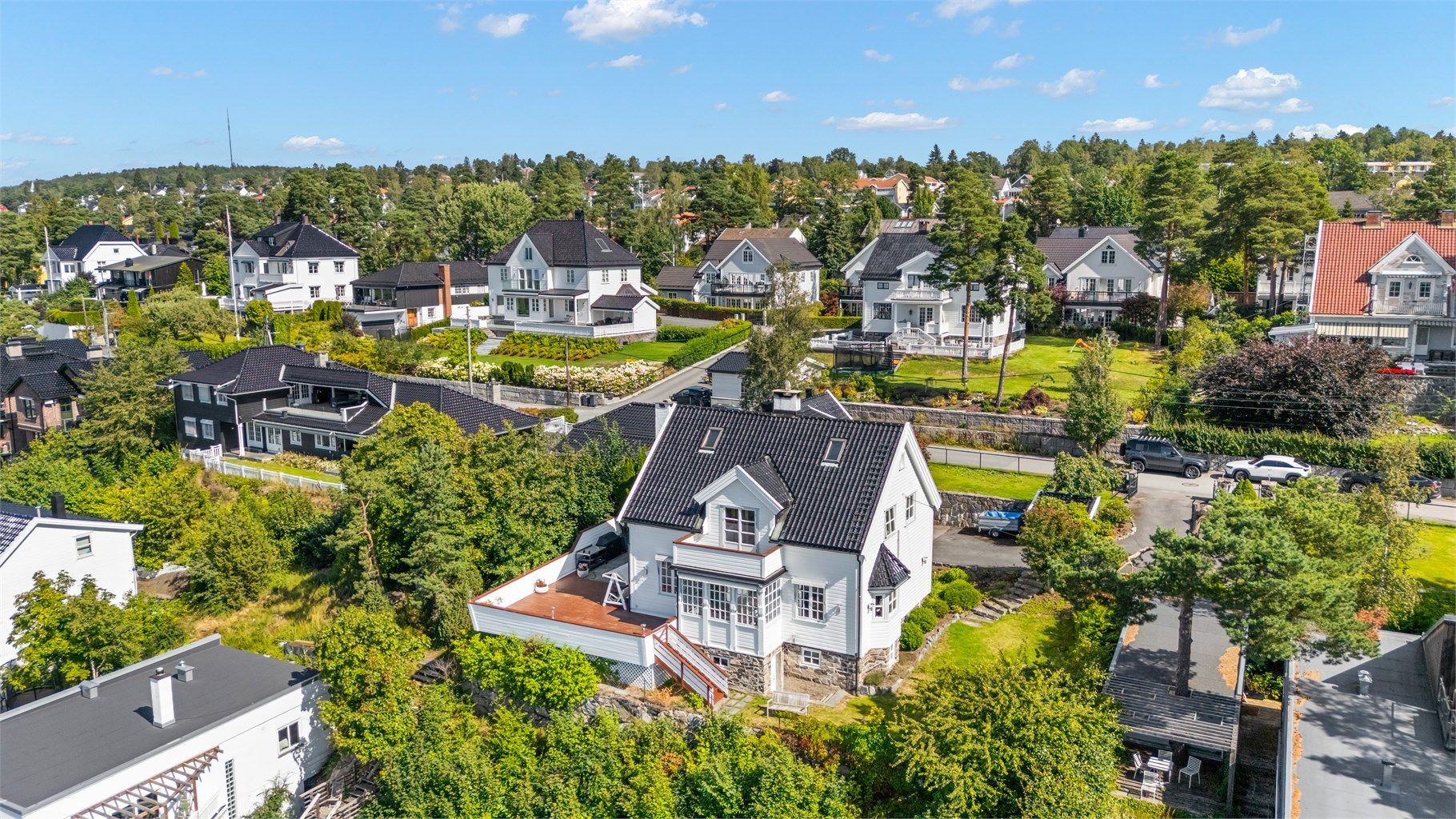 Stor og solrik tomt med utsikt som er pent opparbeidet med plenarealer, prydbusker og diverse beplantning. Asfaltert innkjøring og gårdsplass. Noe naturtomt i skråningen mot vest nedenfor terrassen