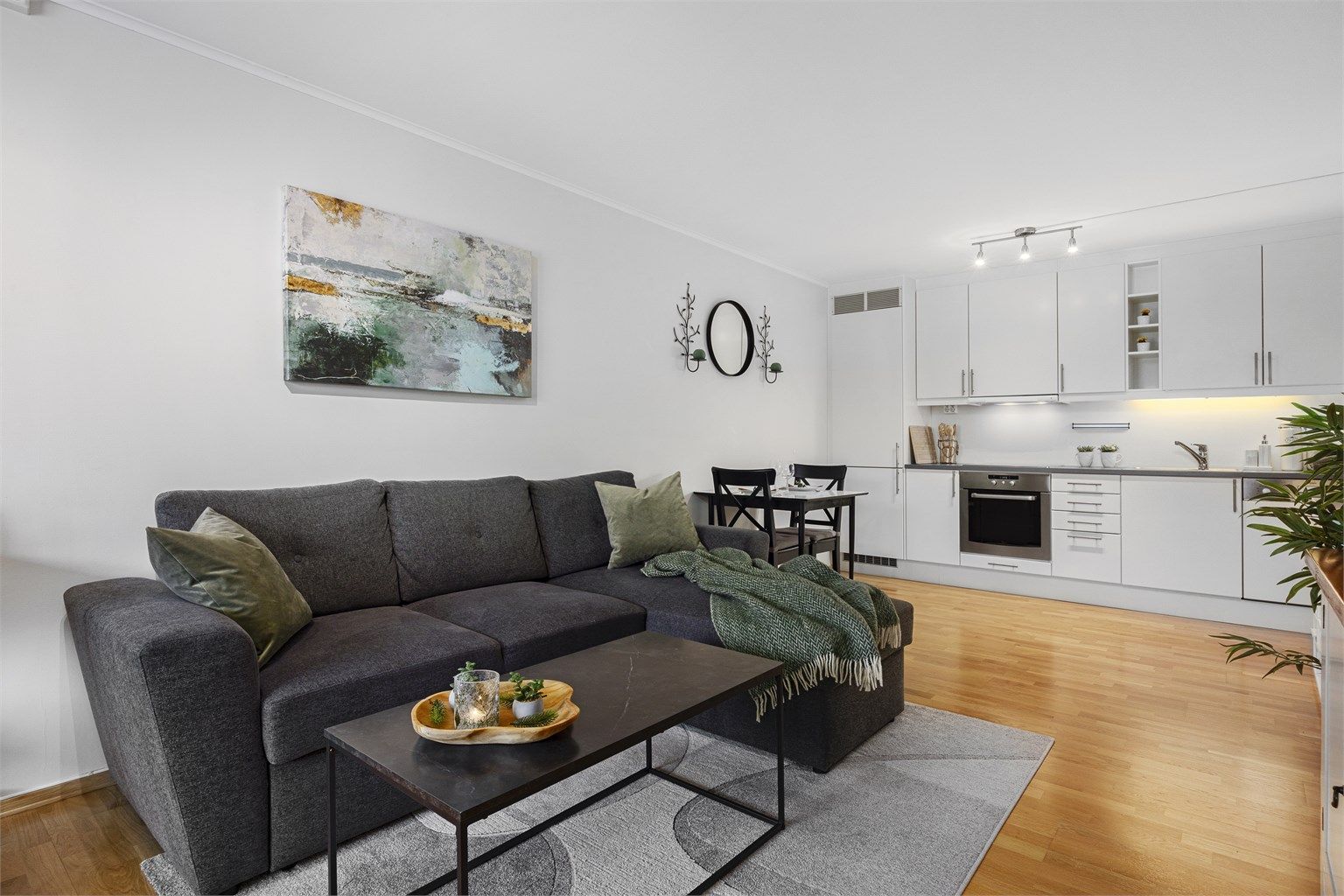 Lys stue i åpen løsning mot kjøkken - god plass til sofa, spisestue og tilhørende møblement.