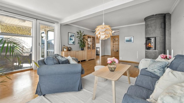 Stuen glir sømløst over i spiseplassen og kjøkkenet, og skaper et stort, sammenhengende oppholdsrom.