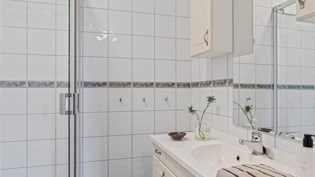 Baderomsinnredning med vegghengt servant og speil med overlys.
