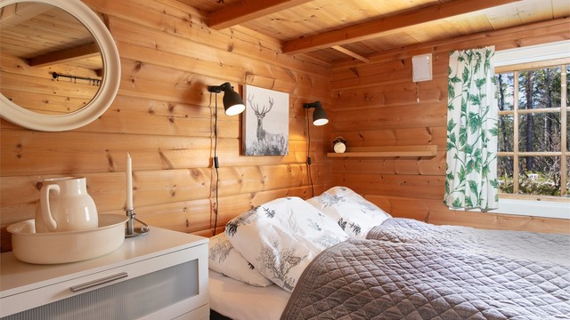 Soverom med vegger og himling i trepanel som gir en varm atmosfære.