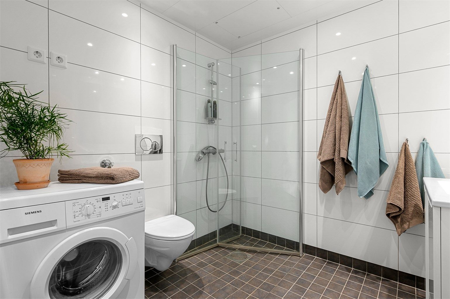 Badet er innredet med servantskap med speil og sideskap, dusjhjørne og vegghengt toalett .