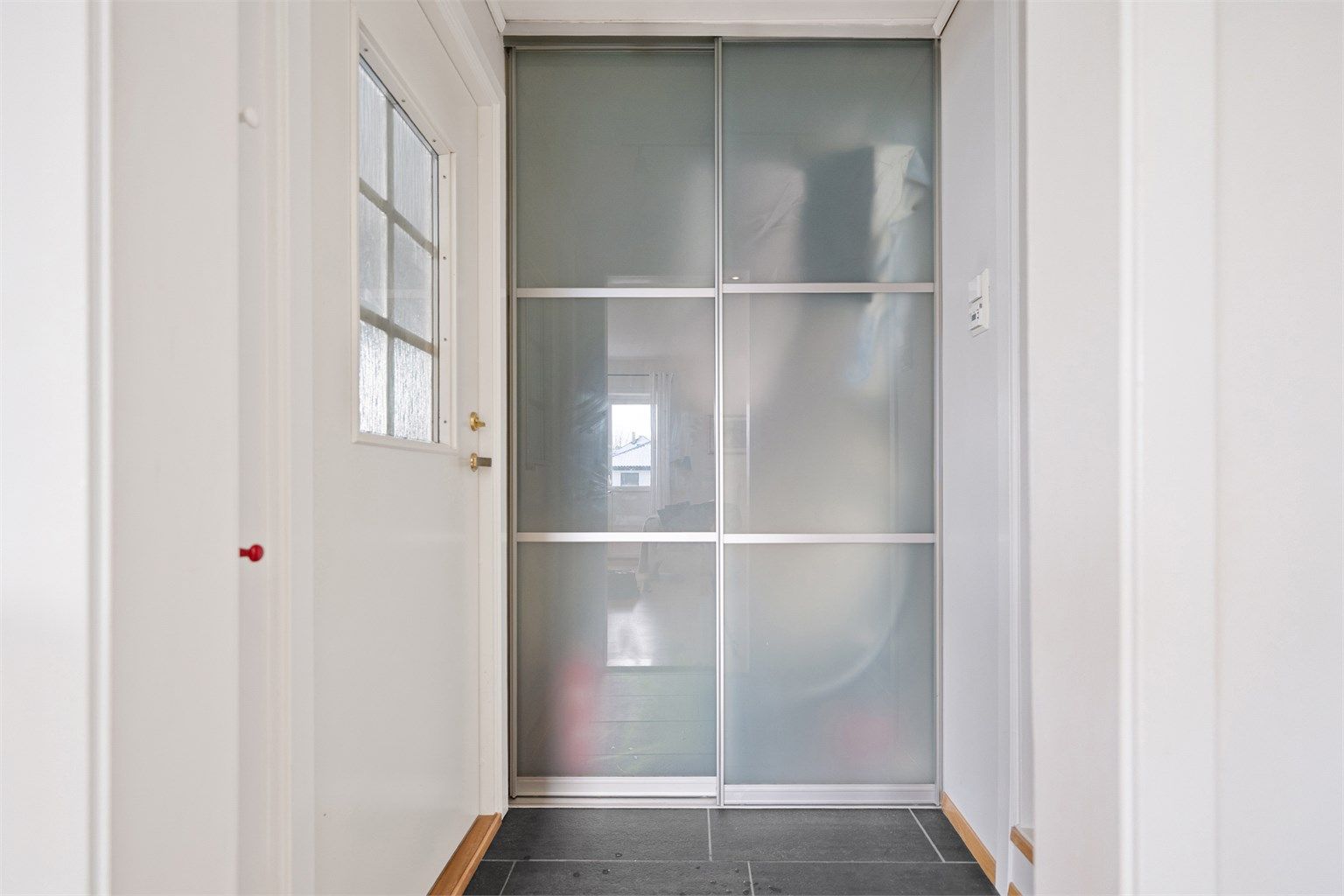 Fliselagt gang med skyvedørsgarderobe. Her er det god plass til yttertøy og sko.