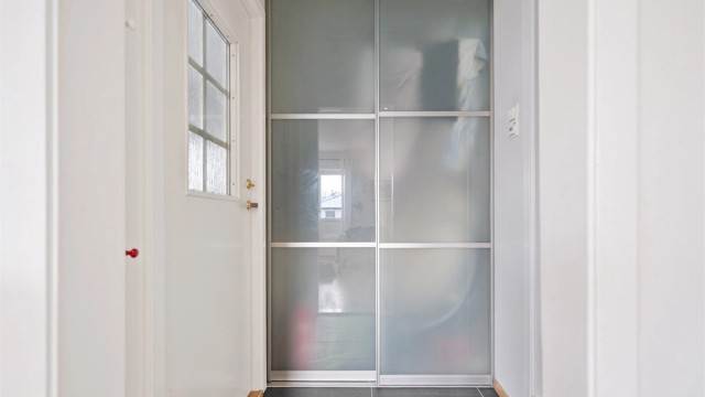Fliselagt gang med skyvedørsgarderobe. Her er det god plass til yttertøy og sko.