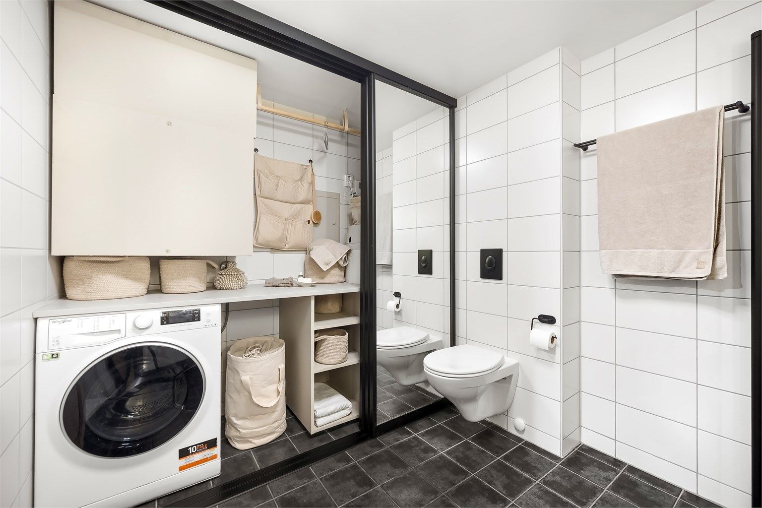 Bak skyvedørene på badet skjuler det seg en smart og arealeffektiv vaskeromsløsning.