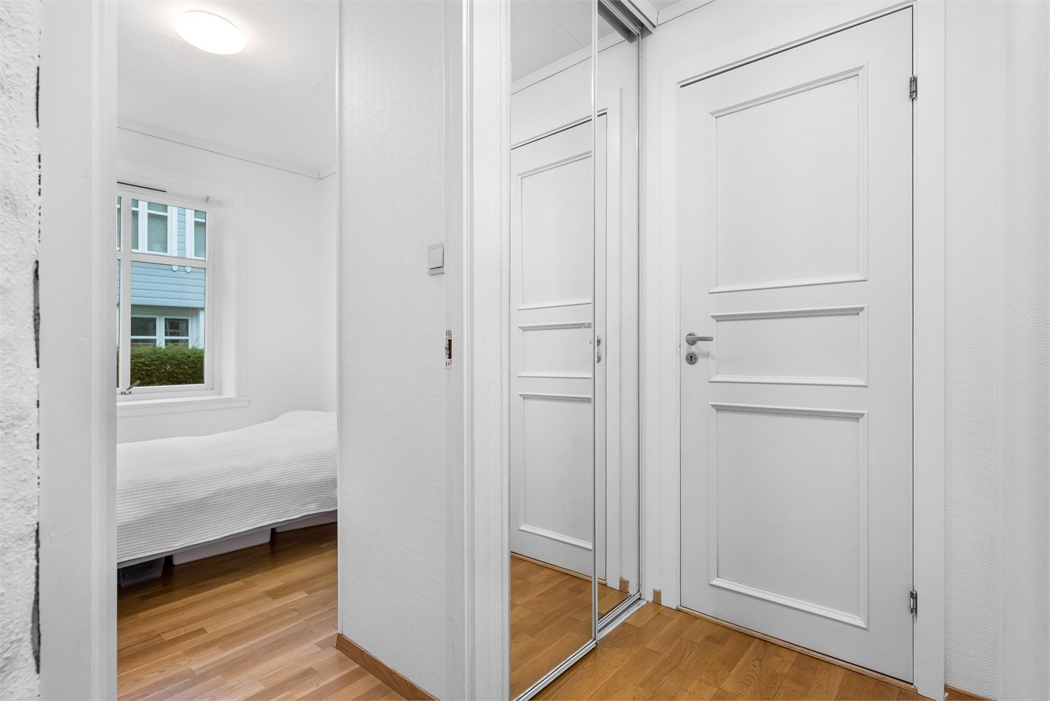 Til venstre i gangen er det montert skyvedørsgarderobe med speil. Dørene på bildet går inn til hvert av soverommene
