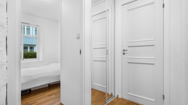Til venstre i gangen er det montert skyvedørsgarderobe med speil. Dørene på bildet går inn til hvert av soverommene