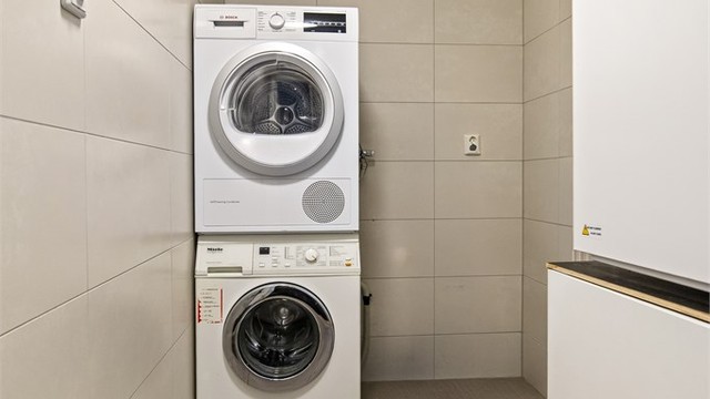 Praktisk, separat vaskerom med flislagt gulv med varme og opplegg for vaskemaskin.