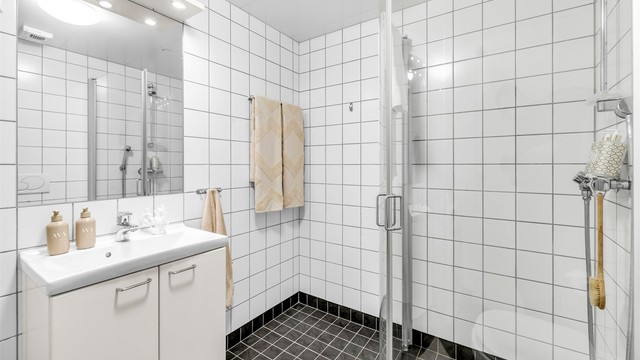 Badet er innredet med vegghengt toalett og servantinnredning med ovenpåliggende vask og speilskap med lys og stikkontakt over vasken.