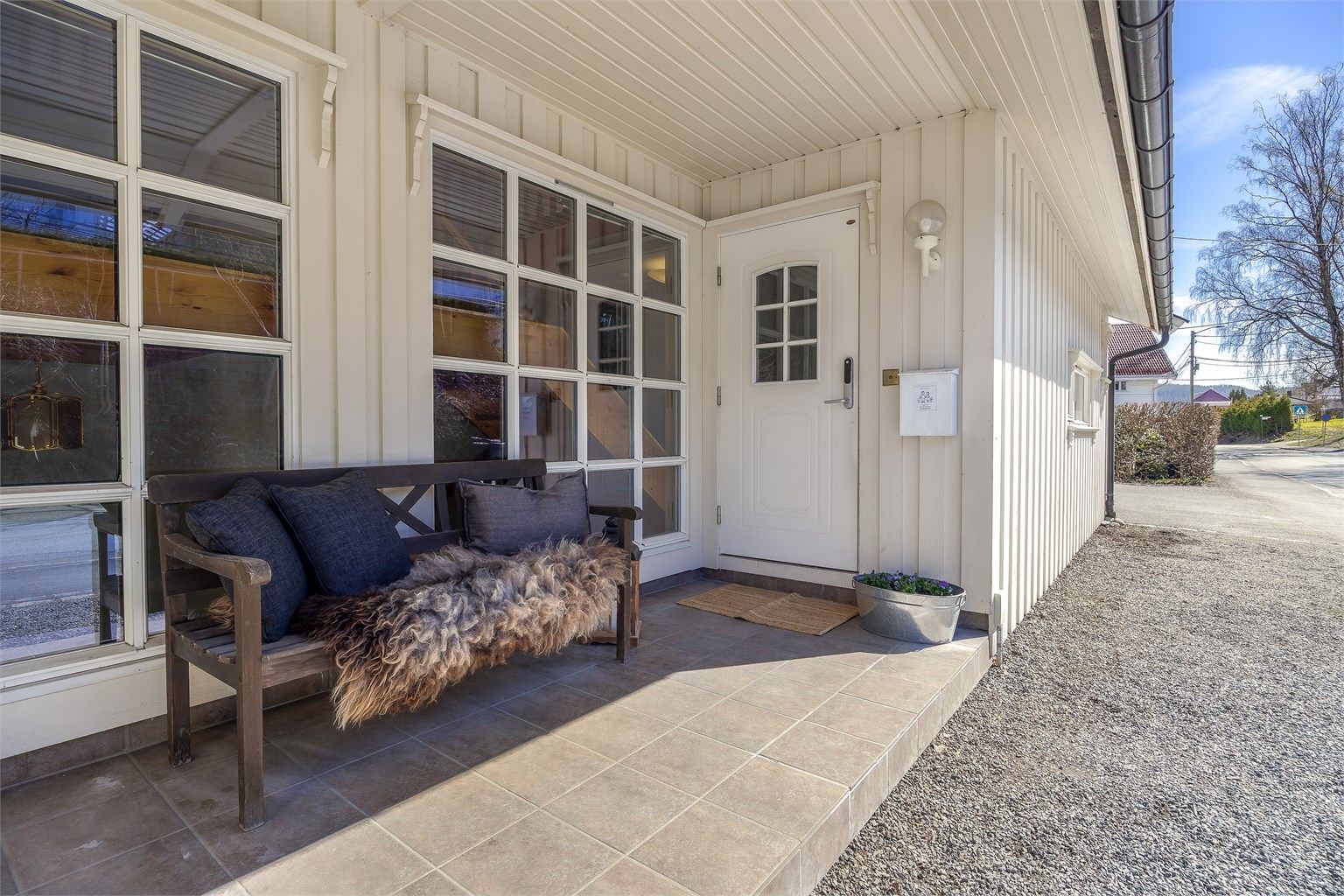 Tilgang til boligens overbygde inngangsparti i 1. etasje. Felles flislagt uteareal ved inngangspartiet.