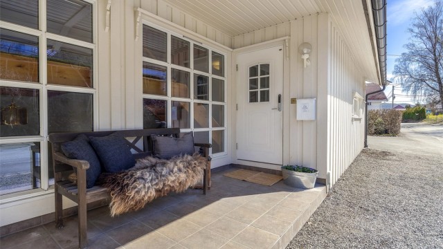 Tilgang til boligens overbygde inngangsparti i 1. etasje. Felles flislagt uteareal ved inngangspartiet.