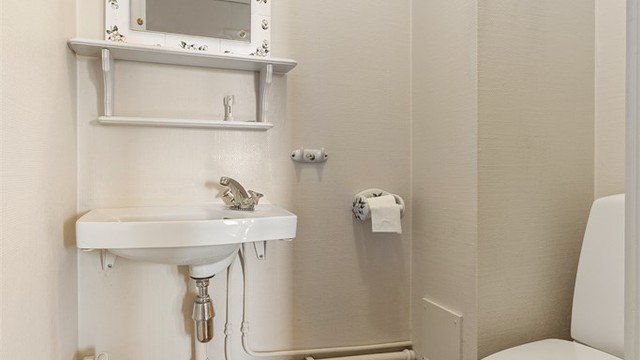 Separat toalettrom utstyrt med gulvstående toalett og vegghengt servant med armatur. Mekanisk avtrekk via veggventil.