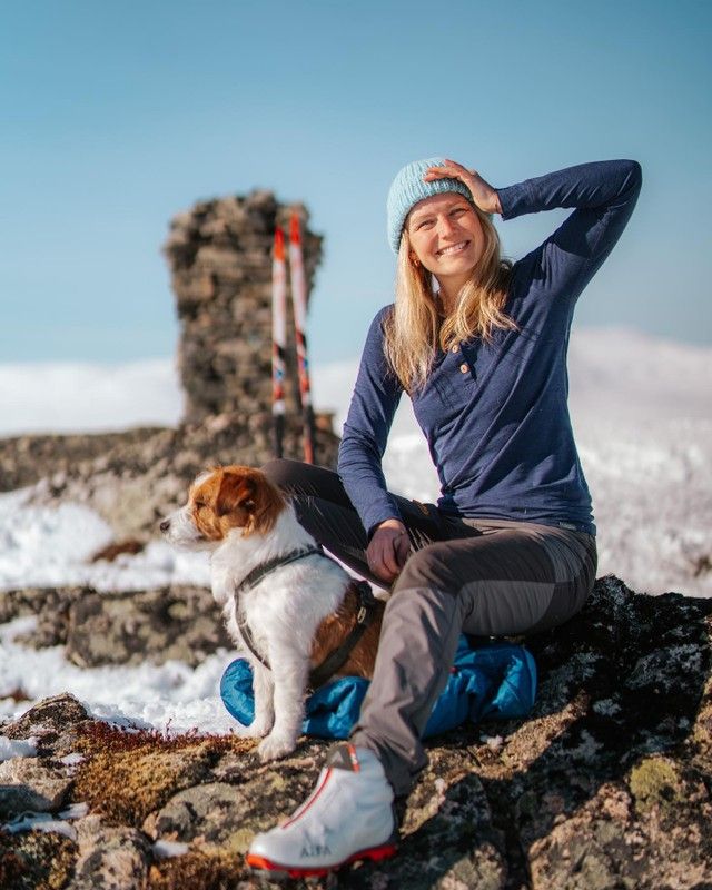 Une Cecilie på toppen av et fjell med hunden sin.