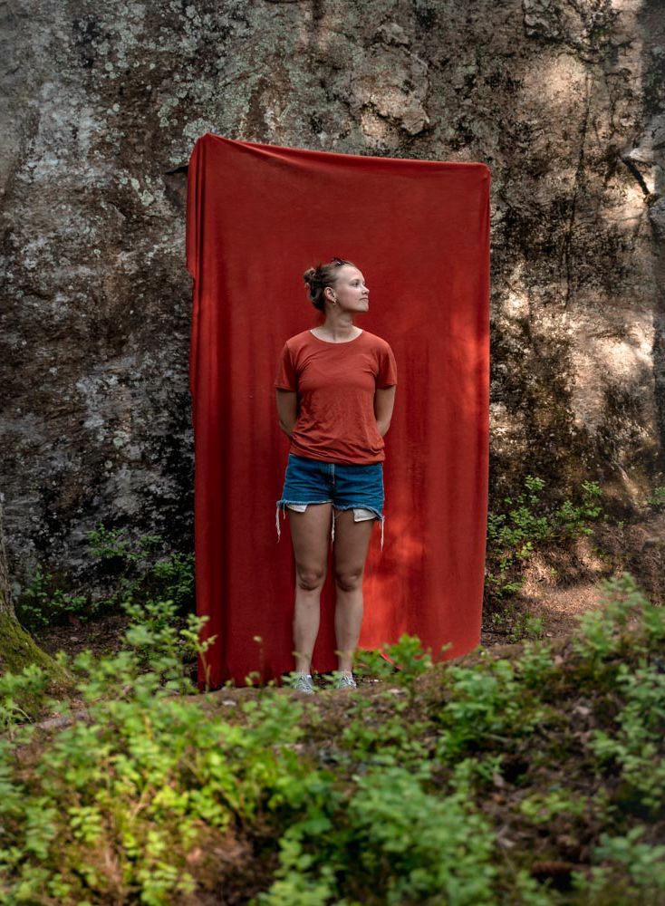 Photo of a woman in front of a large red piece of fabric.